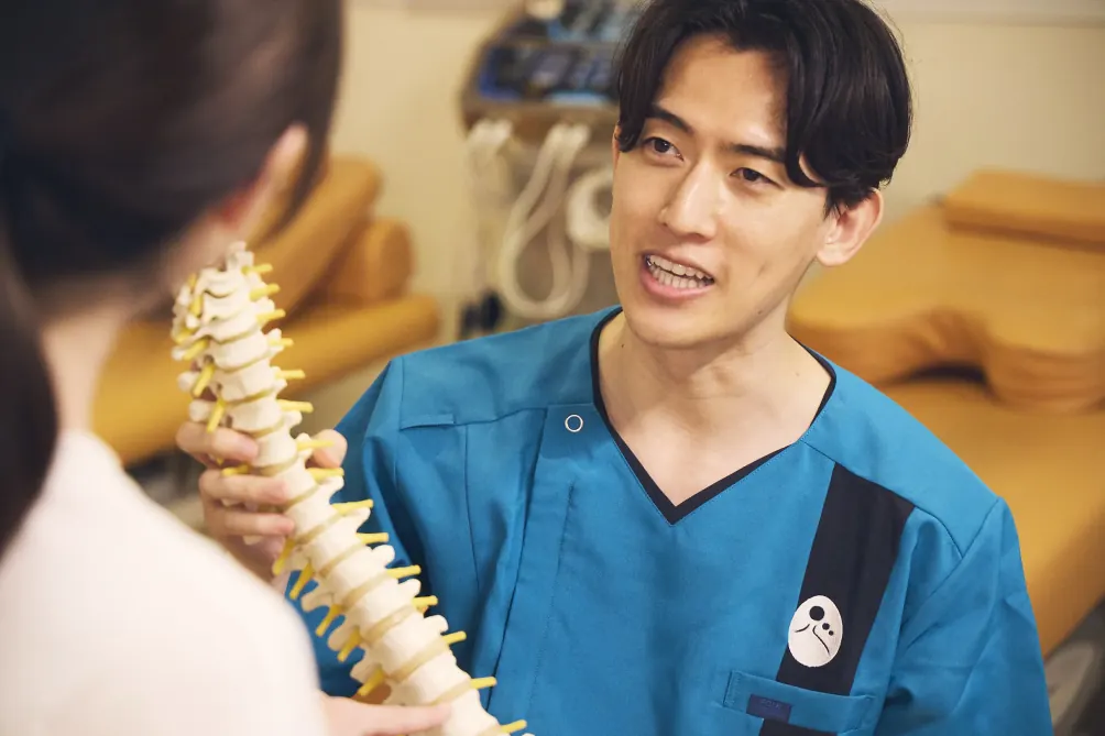 スタッフが背骨模型を使って来院者に説明する様子