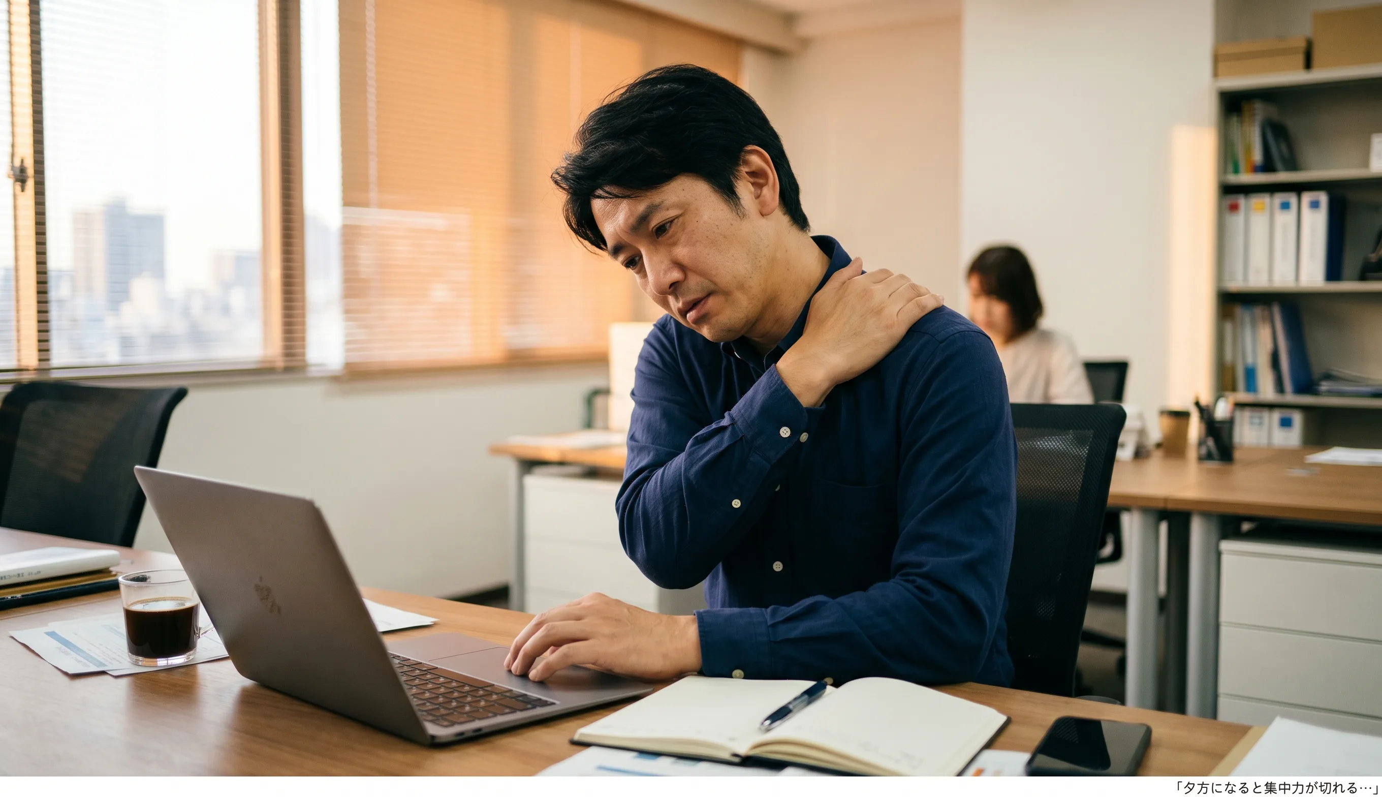 デスクワーク中の40代男性が肩こり・疲労で集中力を失っている様子